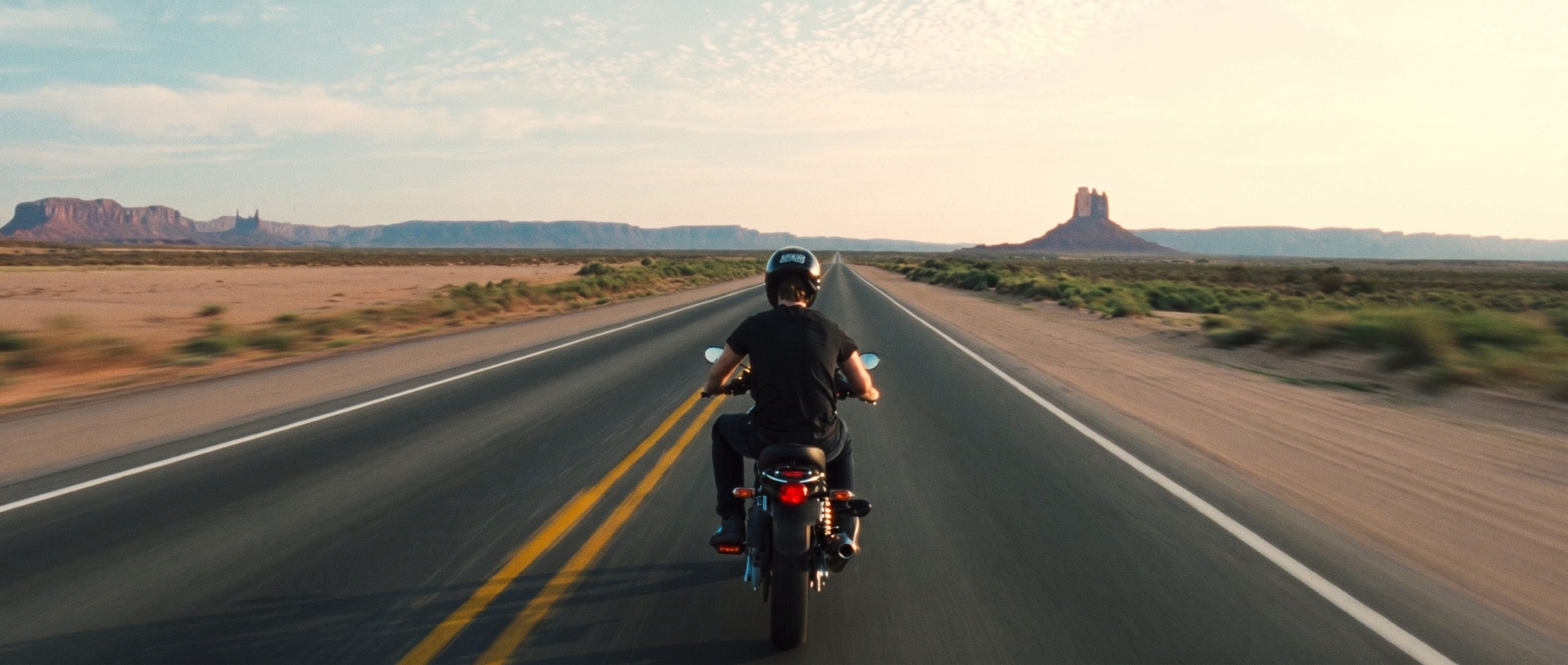 Lone rider on an empty desert highway at golden hour