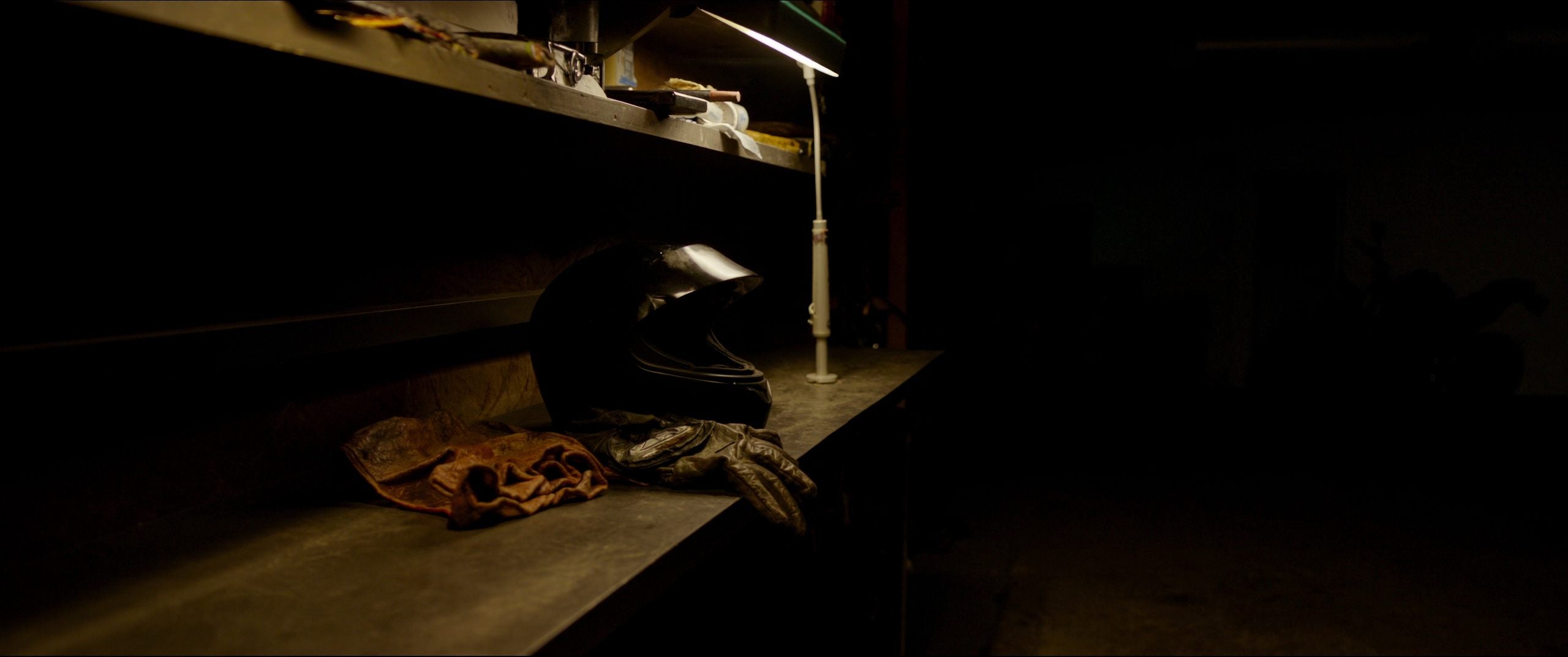 Motorcycle helmet and gloves on a garage workbench at night