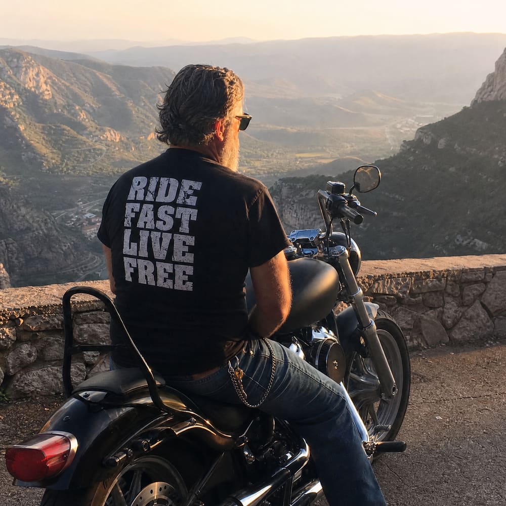 Rider at a mountain overlook wearing a Ride Fast Live Free RIP MOTO tee
