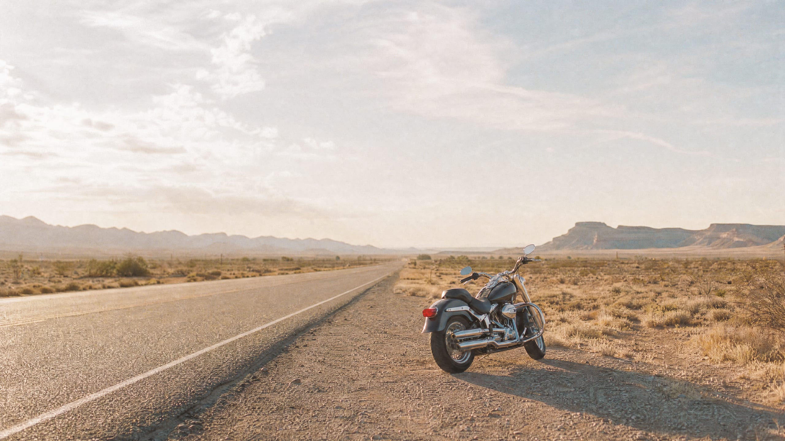 Bright open desert highway with parked cruiser in morning light