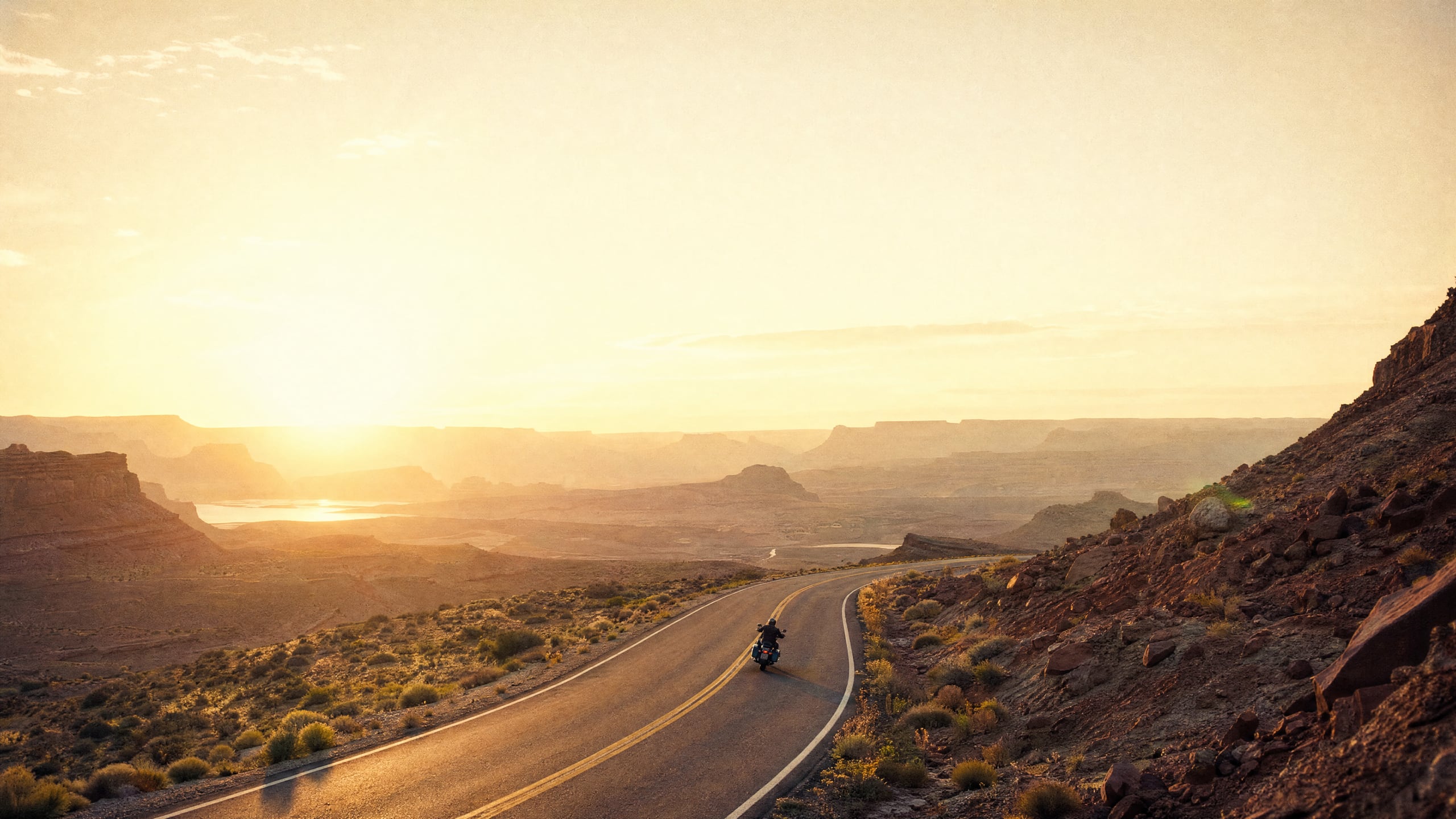 High-angle desert highway at golden hour with lone rider
